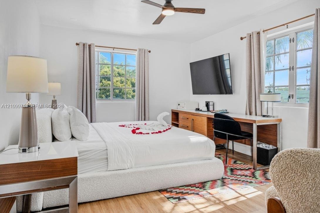 Room featuring wood-finish flooring, dual windows with muntin detailing, and a ceiling fan with integrated lighting
