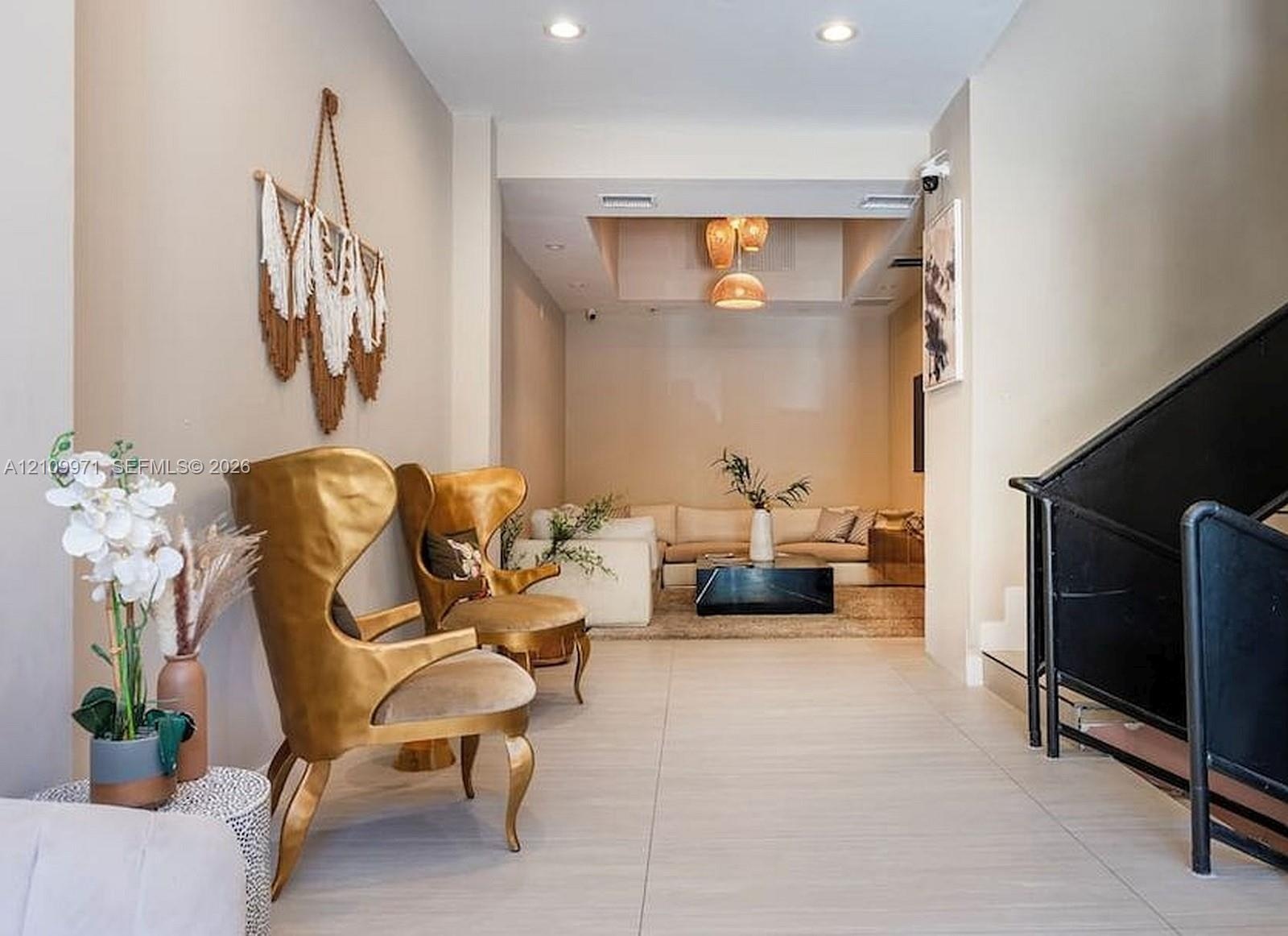 Neutral wall tones, large-format tile flooring, recessed ceiling lighting, multi-tiered pendant lighting, and an industrial-style staircase featuring 