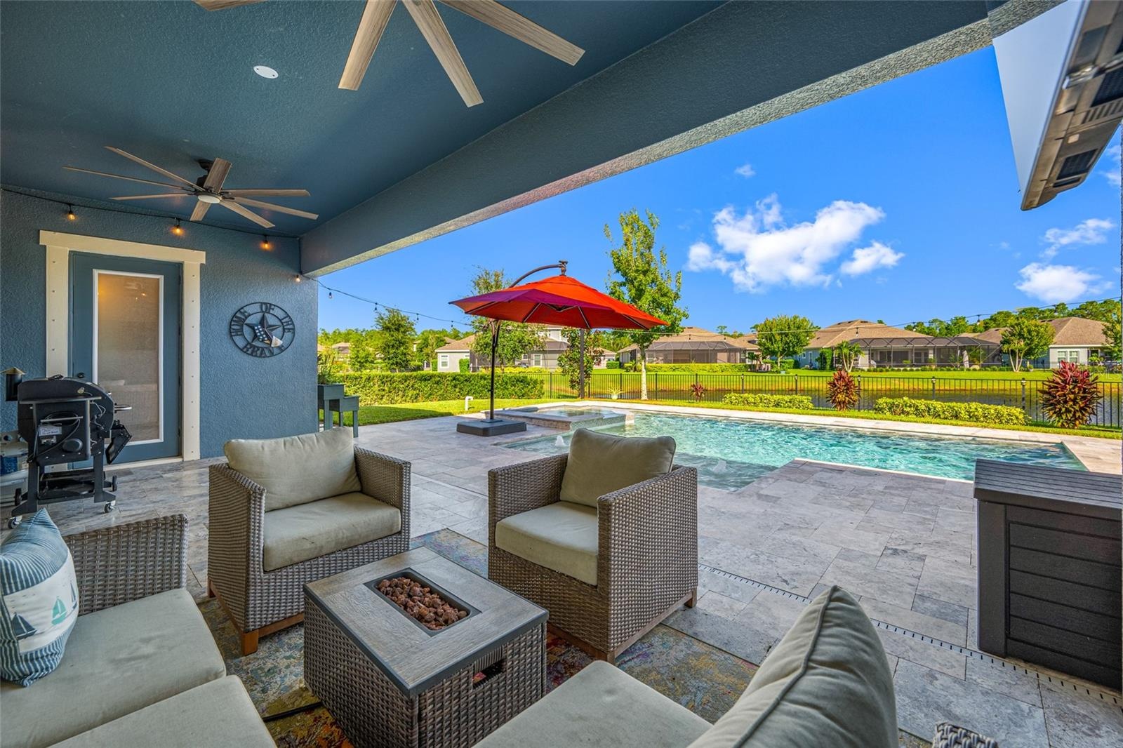 Lanai with pool and spa overlooking fenced backyard on a pond