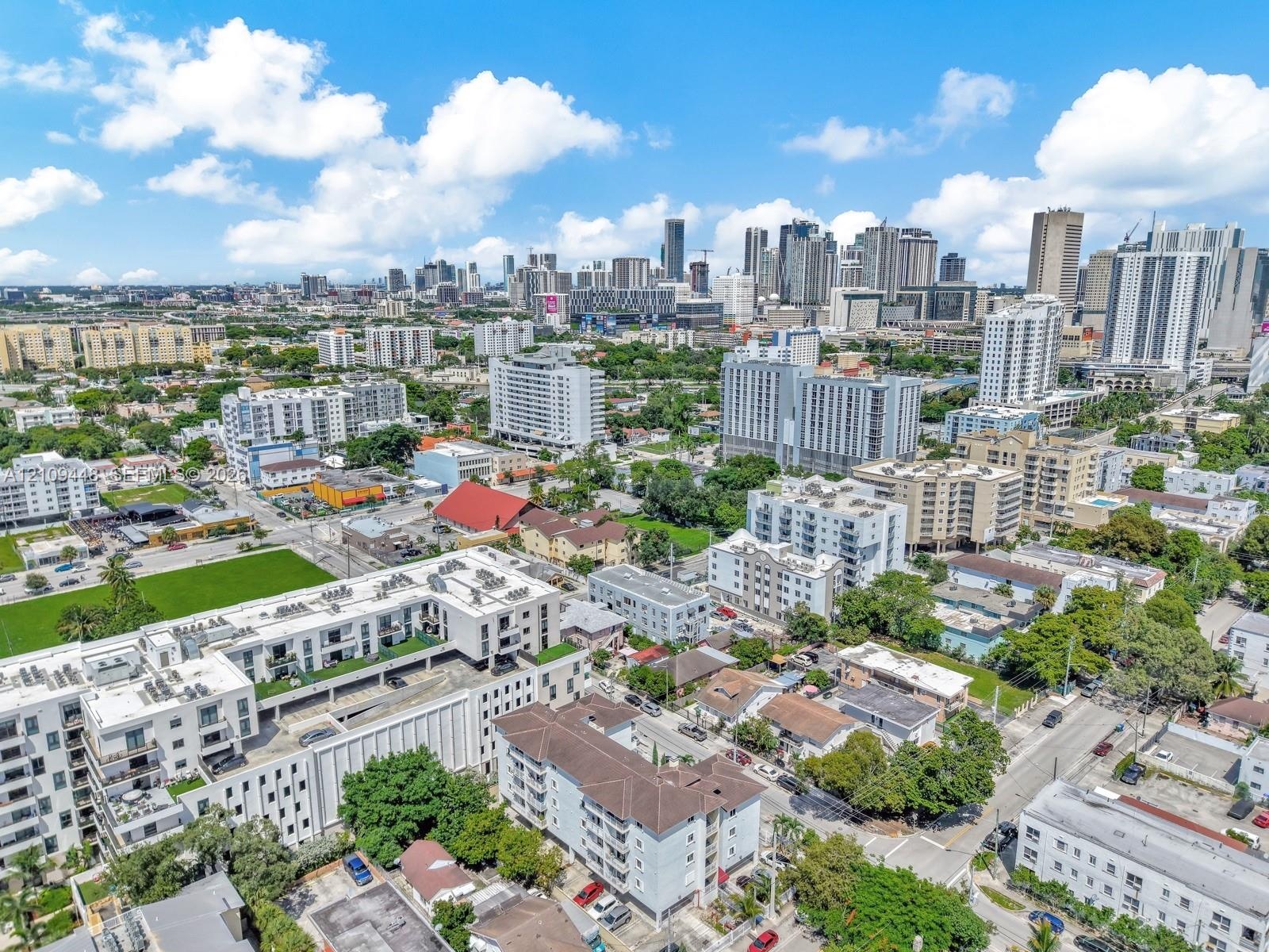 Aerial perspective of a multi-story residential building featuring a structured parking facility, flat roof architecture, and proximity to the urban s