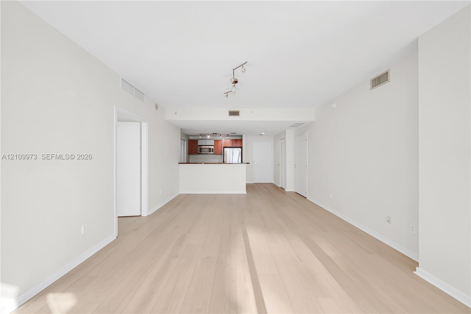 Open-concept interior featuring wood-finish flooring, a kitchen breakfast bar, and track lighting