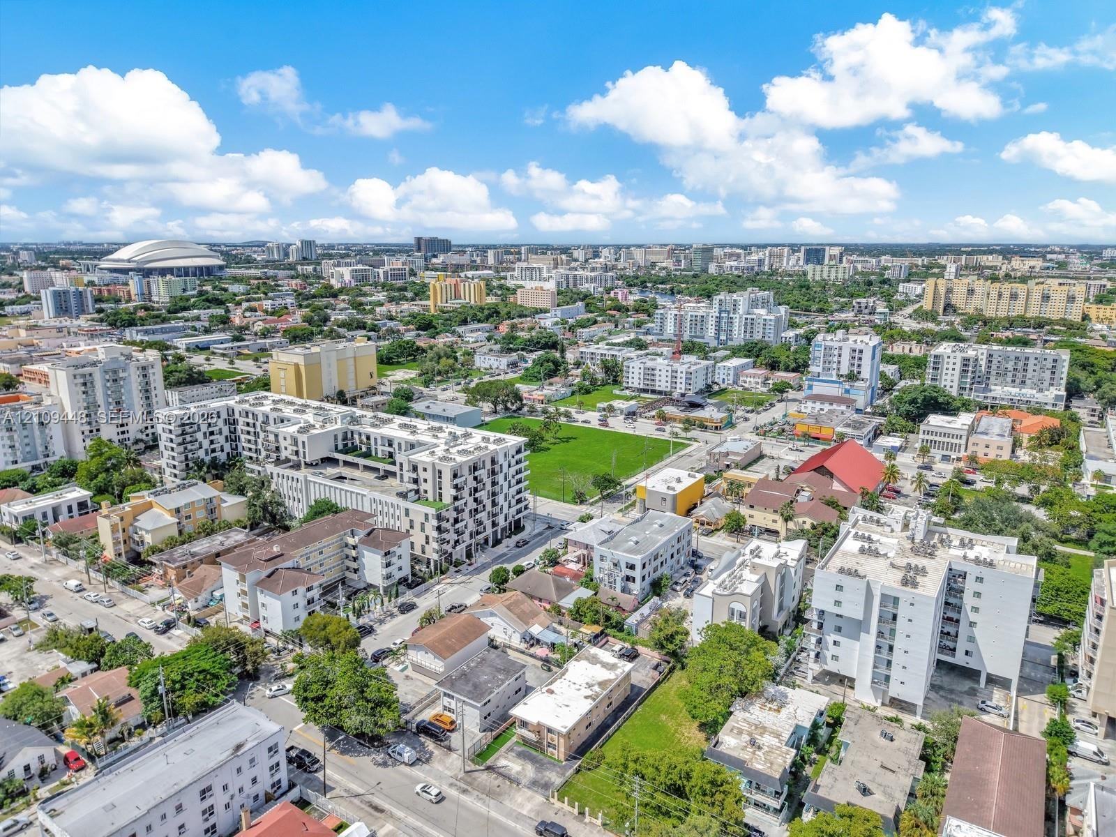 Aerial perspective of a high-density urban environment featuring multi-story residential buildings, paved street grids, landscaped green spaces, and s