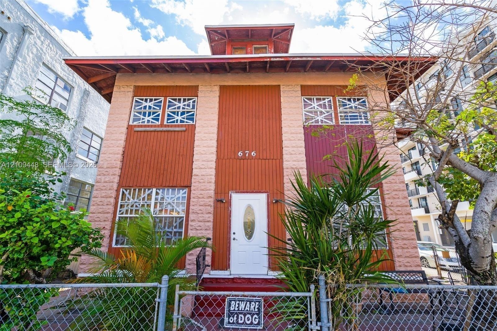 Multi-story exterior featuring a textured masonry facade, vertical panel siding, a roof cupola, and windows with decorative exterior cross-bracing