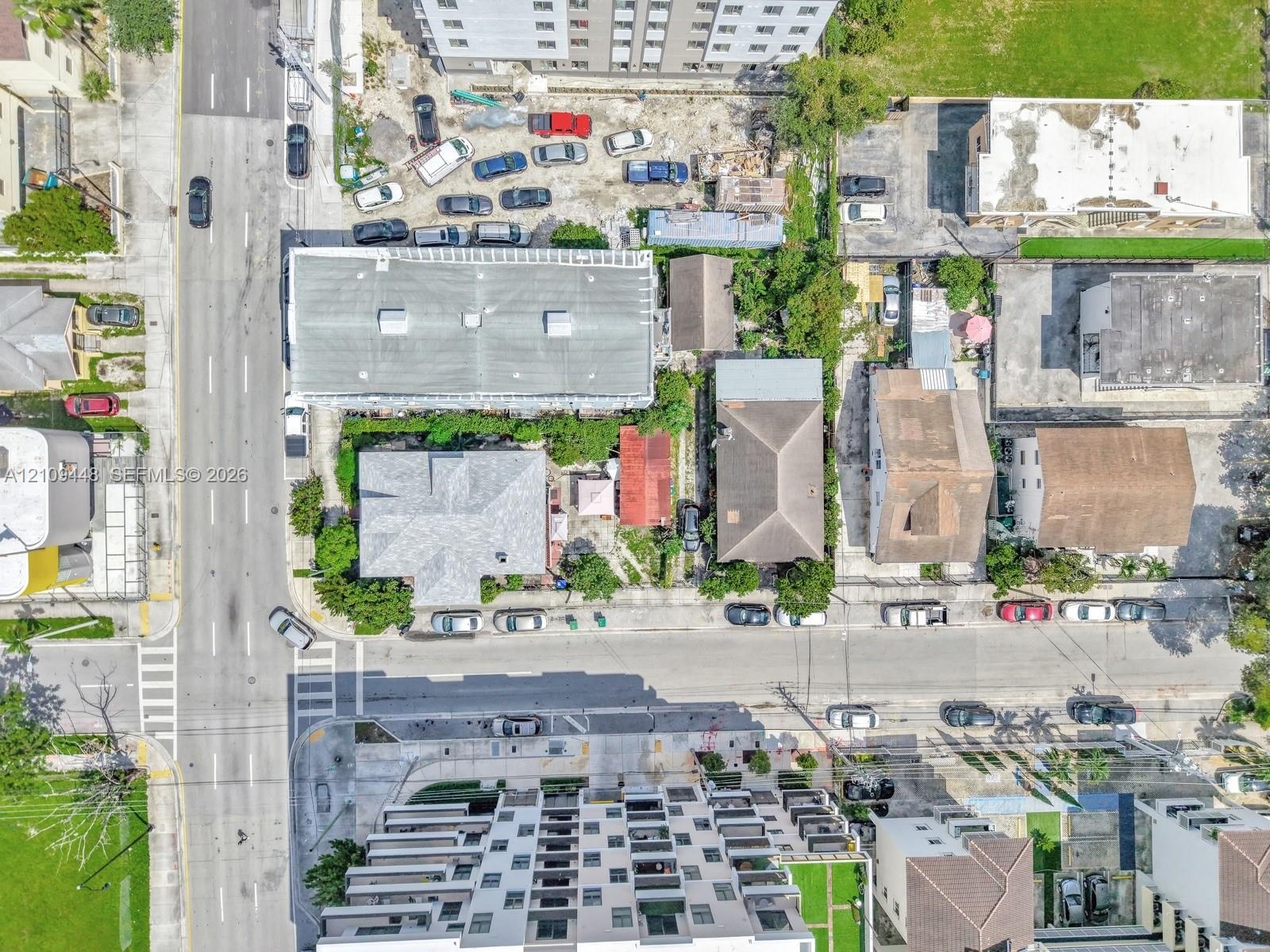 Aerial perspective featuring a multi-story residential structure, paved street access, and dense urban surroundings