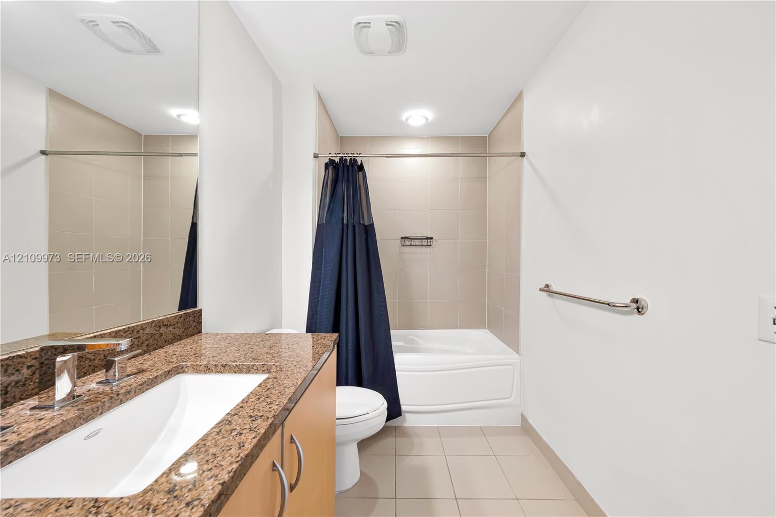 Bathroom featuring a stone-look countertop, integrated sink, vanity cabinetry, and a tub-shower combination with tile surround