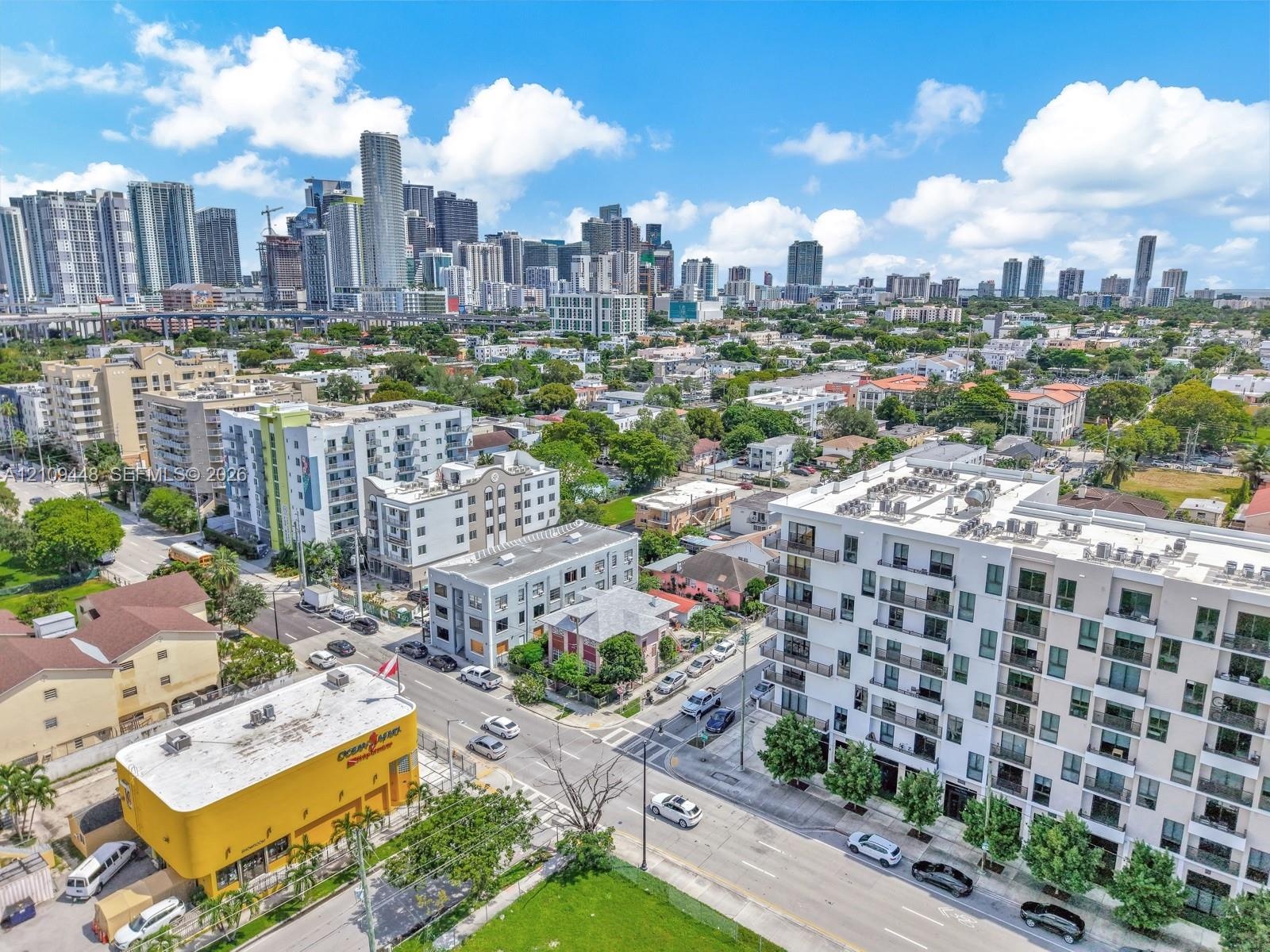 Aerial perspective of a multi-story residential building featuring private balconies, floor-to-ceiling windows, and a flat-roof design, set against a 