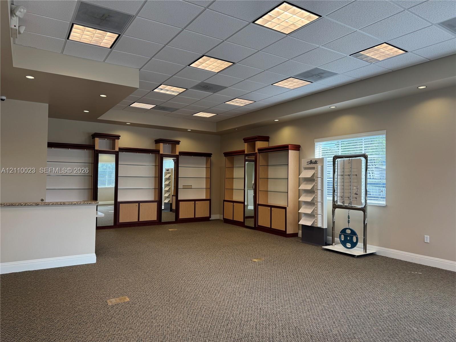 Spacious interior featuring integrated floor-to-ceiling cabinetry, recessed lighting, grid-pattern drop ceiling, and neutral carpeting