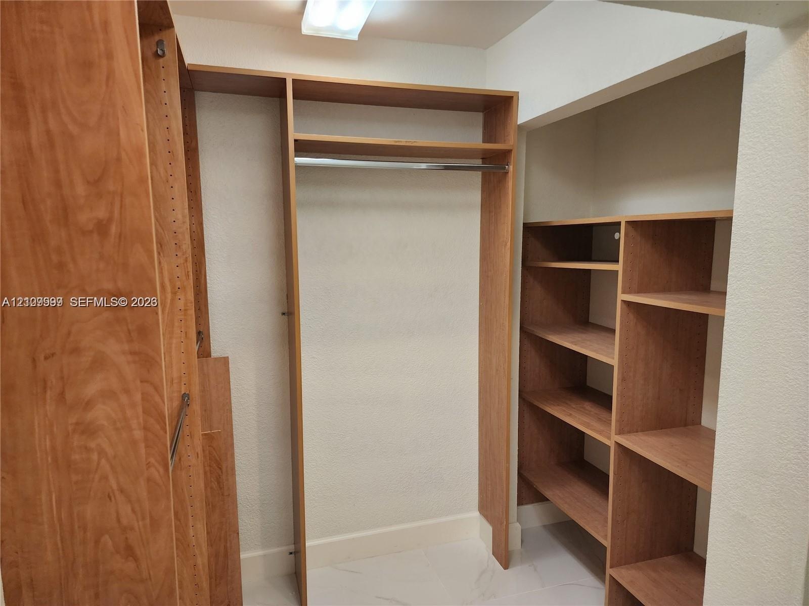 Custom wood-finish closet system featuring vertical shelving units, horizontal storage racks, and an integrated hanging rod