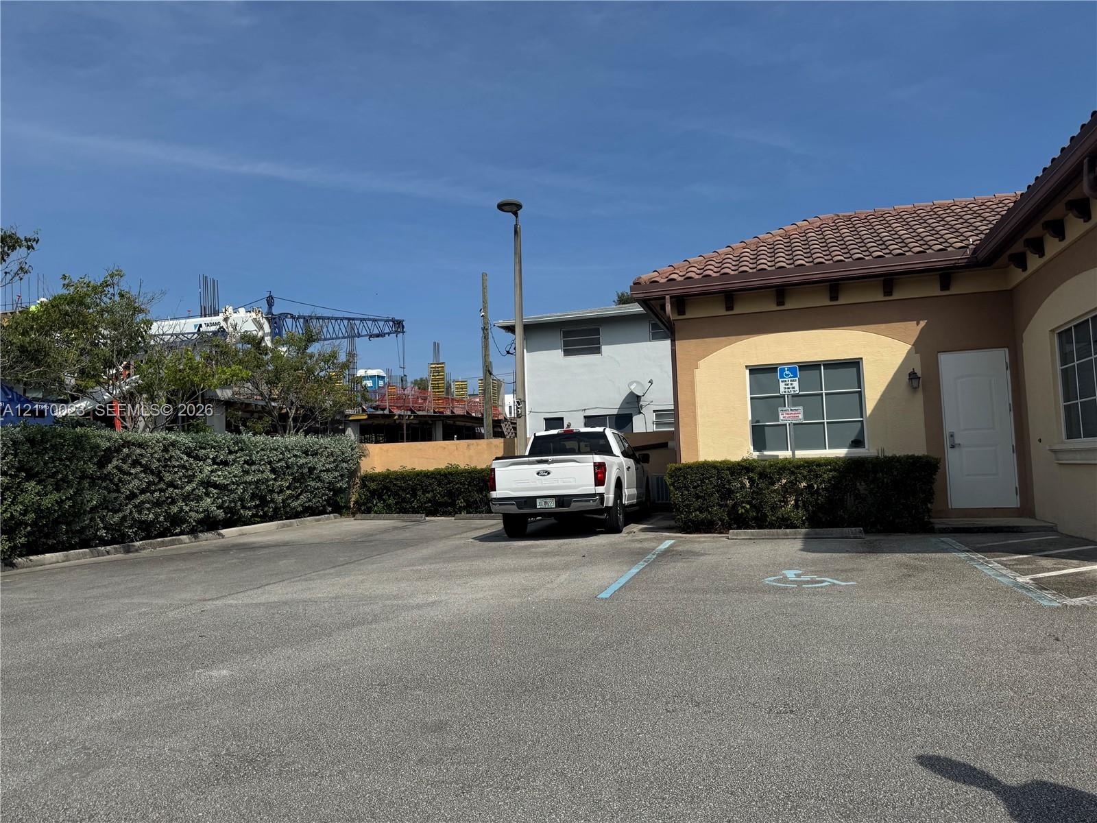 Paved exterior parking area with designated accessibility stalls, stucco facade, and tile roof
