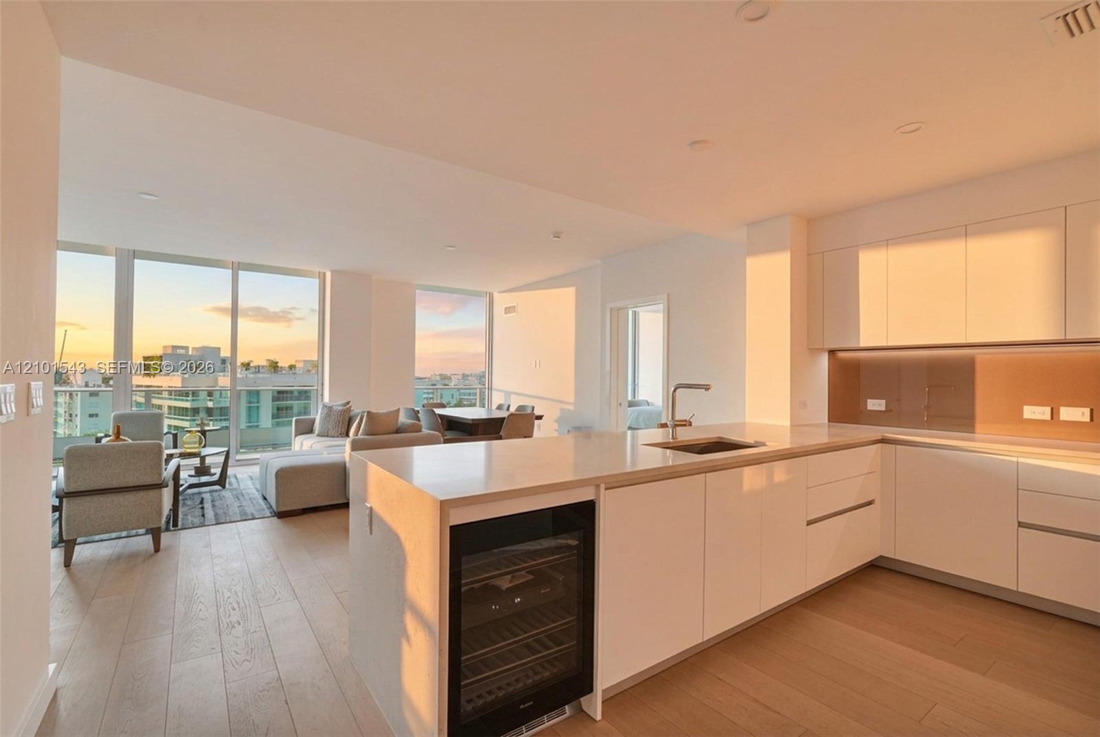 Kitchen featuring high-gloss cabinetry, stone countertops, integrated wine refrigeration, wood-finish flooring, and floor-to-ceiling windows