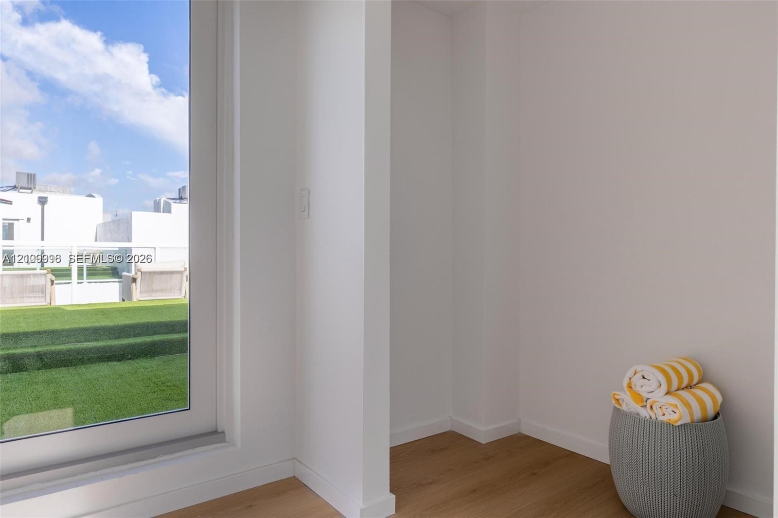 Full-height glass door with white frame, wood-finish flooring, and recessed wall alcove