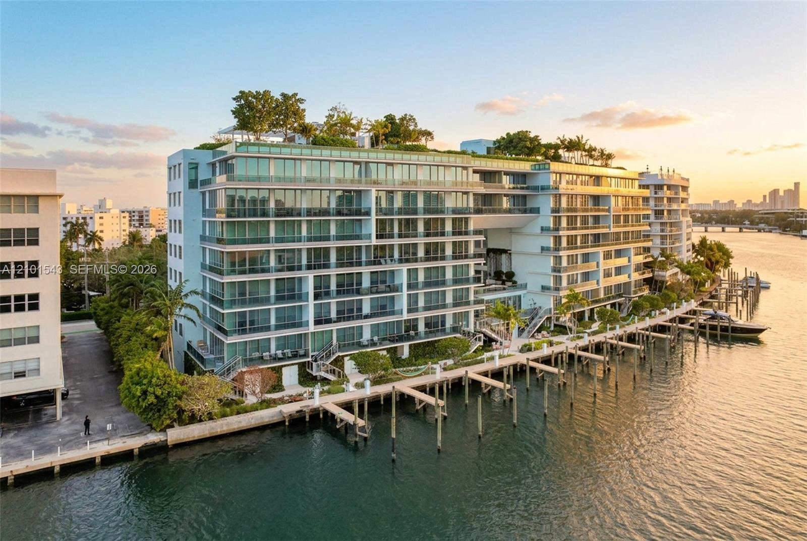 Waterfront residential complex featuring multiple levels of glass-railed balconies, a rooftop terrace, private deep-water dockage, and expansive floor