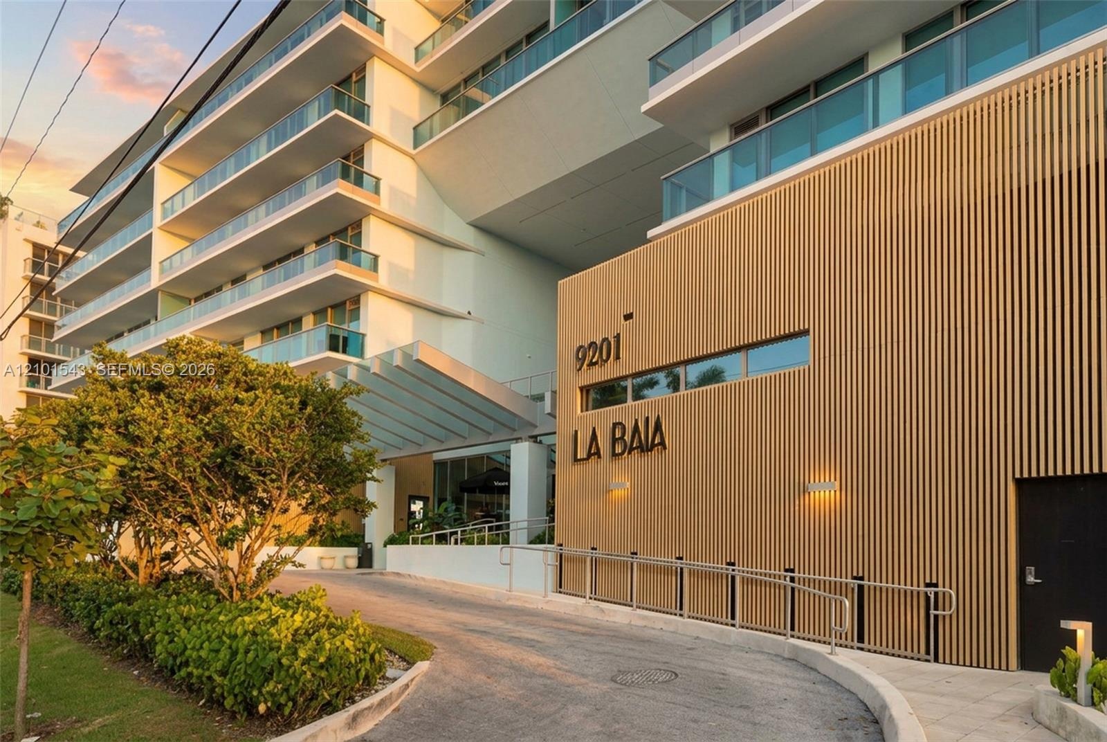 Contemporary architectural exterior featuring vertical wood-slat cladding, multi-level balconies with glass railings, and a covered porte-cochère entr