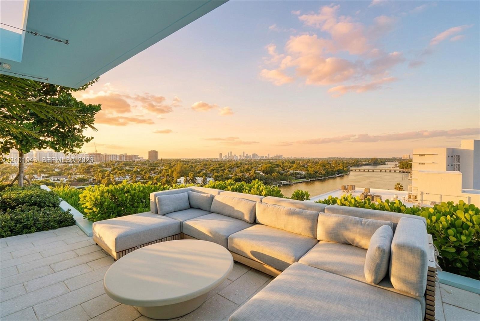 Expansive rooftop terrace featuring stone paver flooring, built-in planters with mature greenery, and a structural overhang