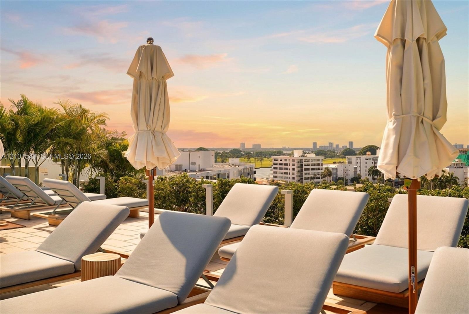 Rooftop terrace featuring light-toned tile flooring, lush perimeter landscaping, and a panoramic skyline backdrop