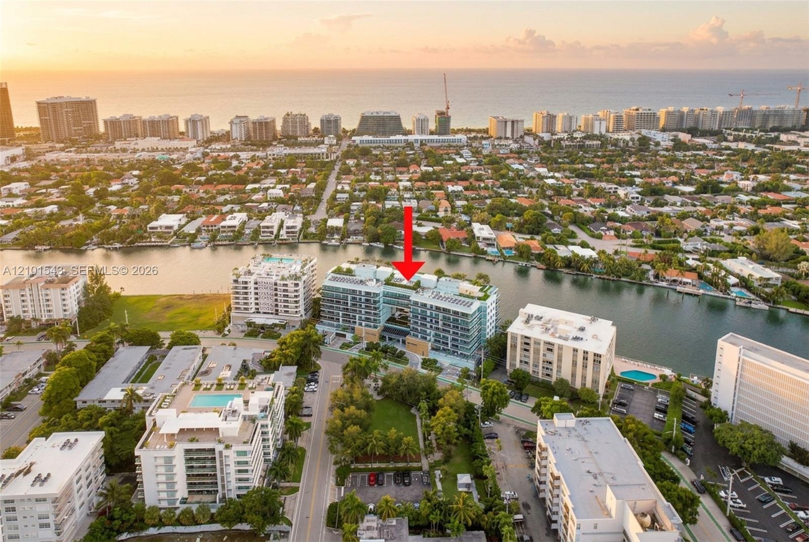 Multi-story residential building featuring floor-to-ceiling glass paneling, a rooftop pool, private balconies, and waterfront positioning along a cana