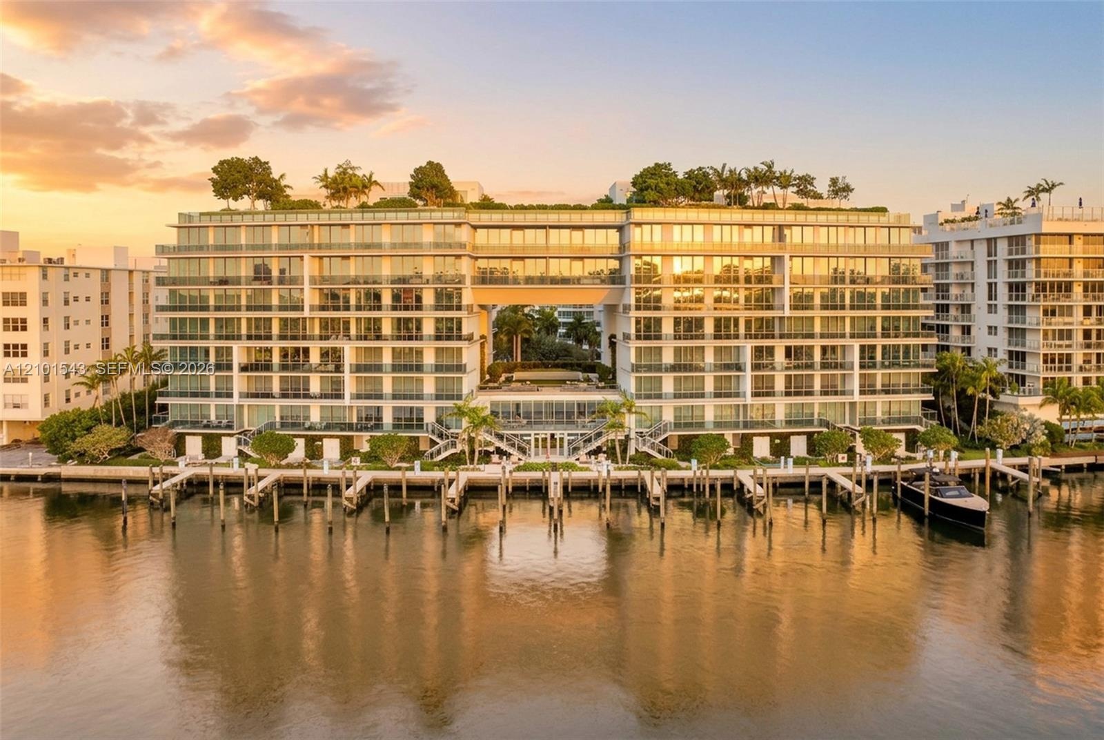 Waterfront residential building featuring floor-to-ceiling glass exteriors, expansive private balconies, a rooftop garden, and multiple deep-water boa