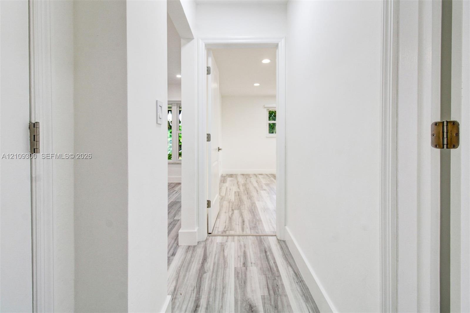 Interior hallway featuring neutral walls, wood-finish flooring, recessed lighting, and white door casings