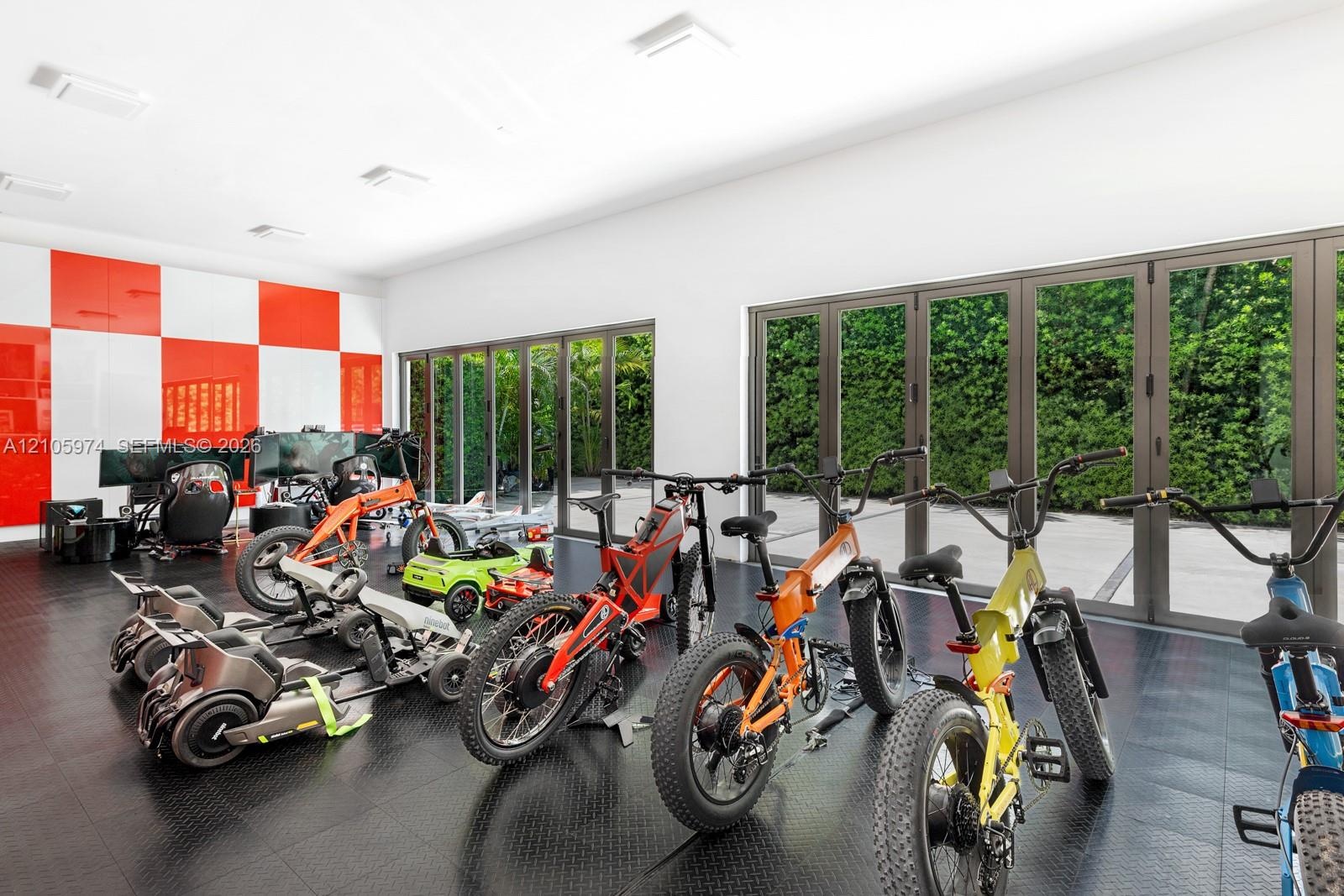 Expansive room featuring high-gloss red and white wall panels, durable rubberized diamond-plate flooring, and two sets of multi-panel aluminum-framed 