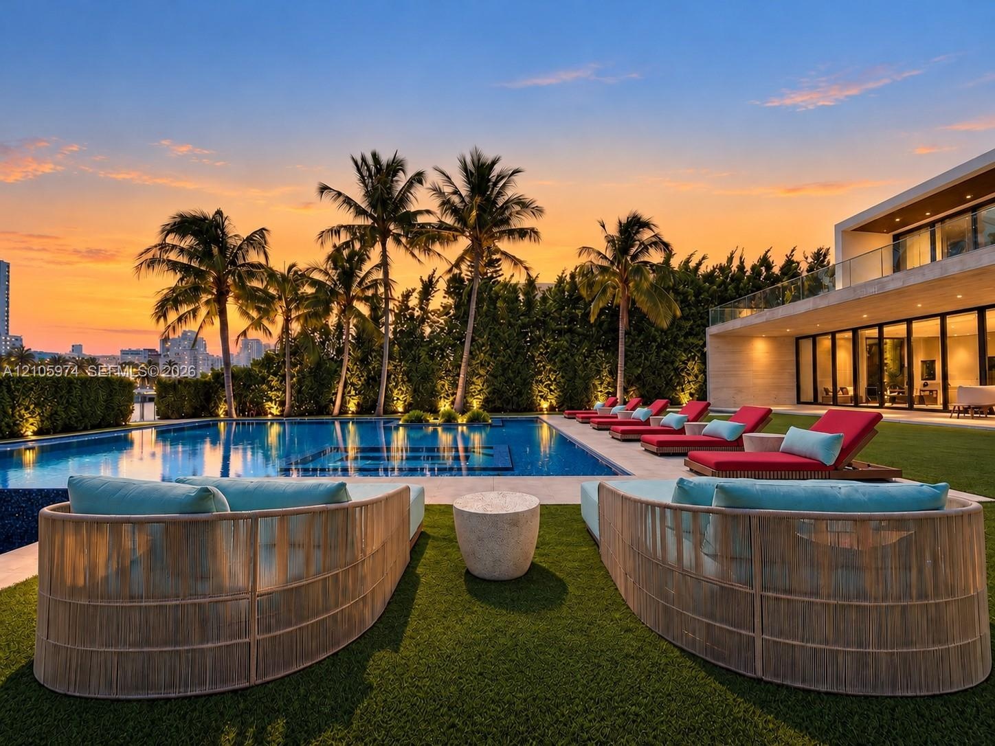Outdoor living space featuring an inground swimming pool with stone tiling, synthetic grass lawn, perimeter hedges, and a glass-railed second-level ba