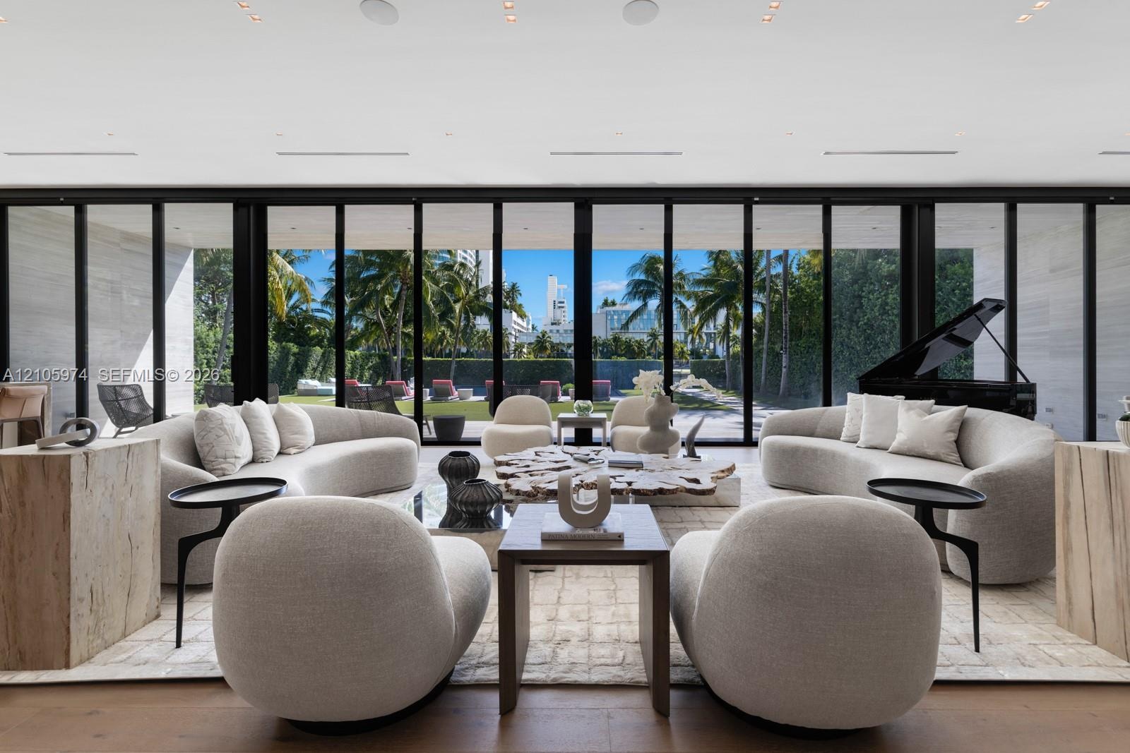 Floor-to-ceiling retractable glass walls, wide-plank wood-finish flooring, recessed ceiling lighting, and expansive stone-clad wall accents