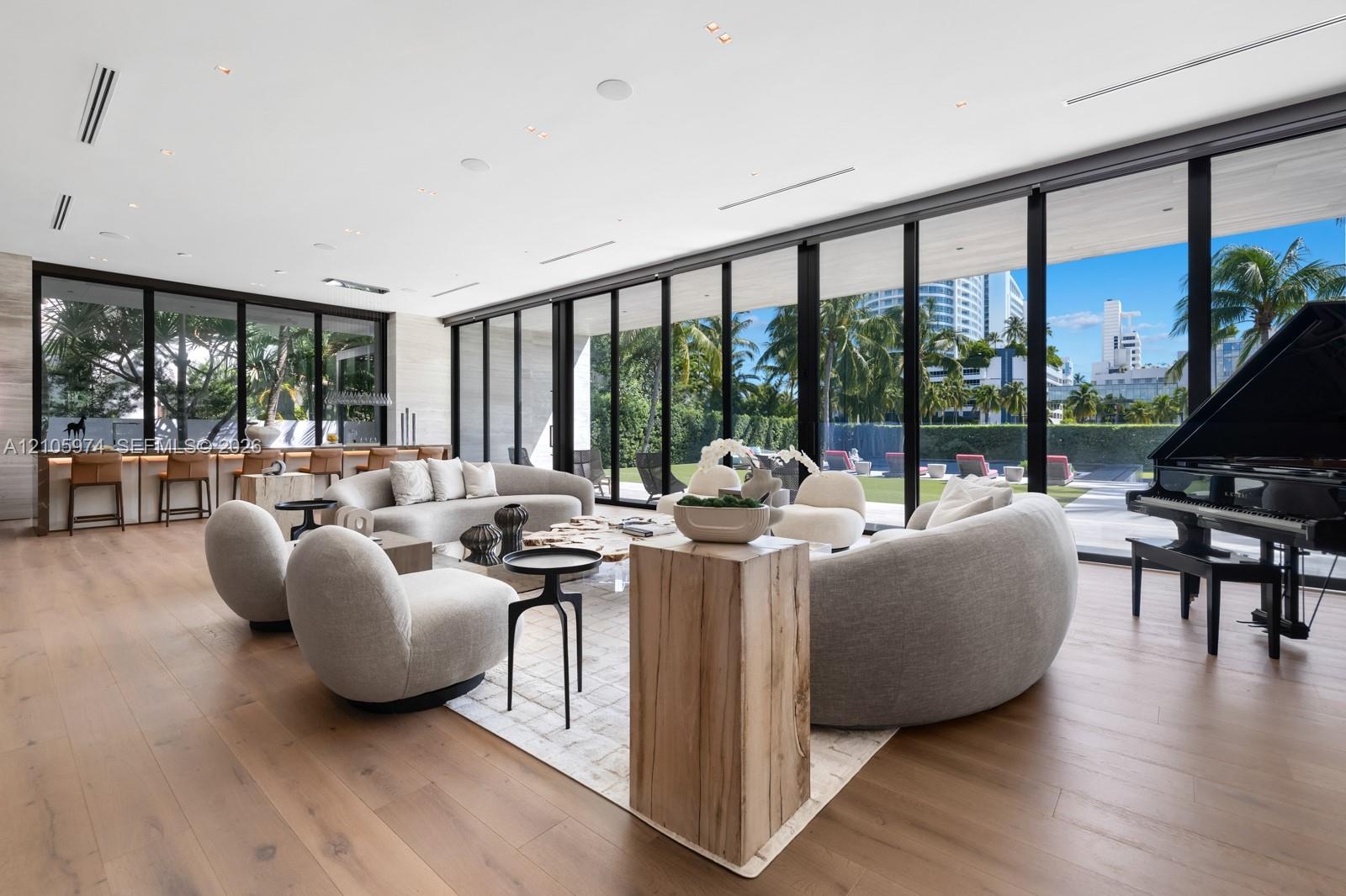 Floor-to-ceiling glass wall systems, wood-finish flooring, built-in wet bar, recessed ceiling lighting, and custom stone wall cladding