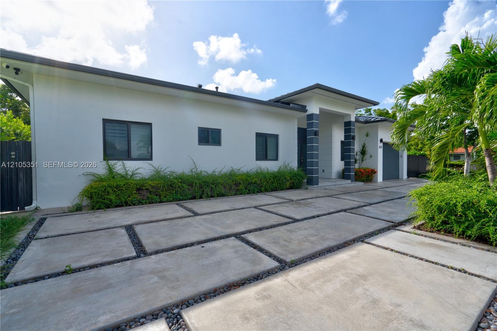 Contemporary exterior featuring smooth stucco finish, geometric concrete paver driveway with decorative stone accents, covered entryway with stone-cla
