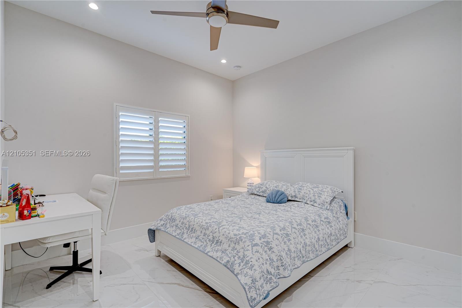 Neutral-toned bedroom featuring large-format tile flooring, recessed ceiling lighting, a contemporary ceiling fan, and plantation shutters