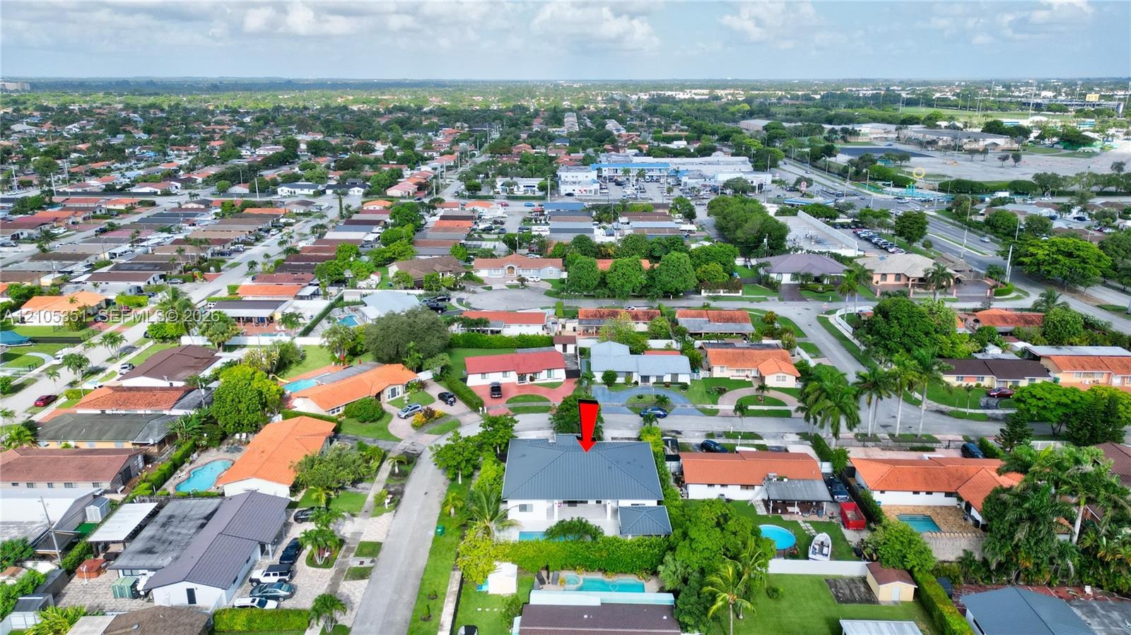 Aerial perspective of a residential property featuring a pitched roof, a swimming pool, and established landscaping