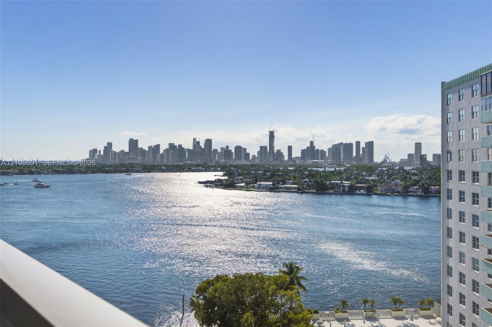 Elevated balcony with a metallic railing overlooking an expansive waterway and a prominent urban skyline