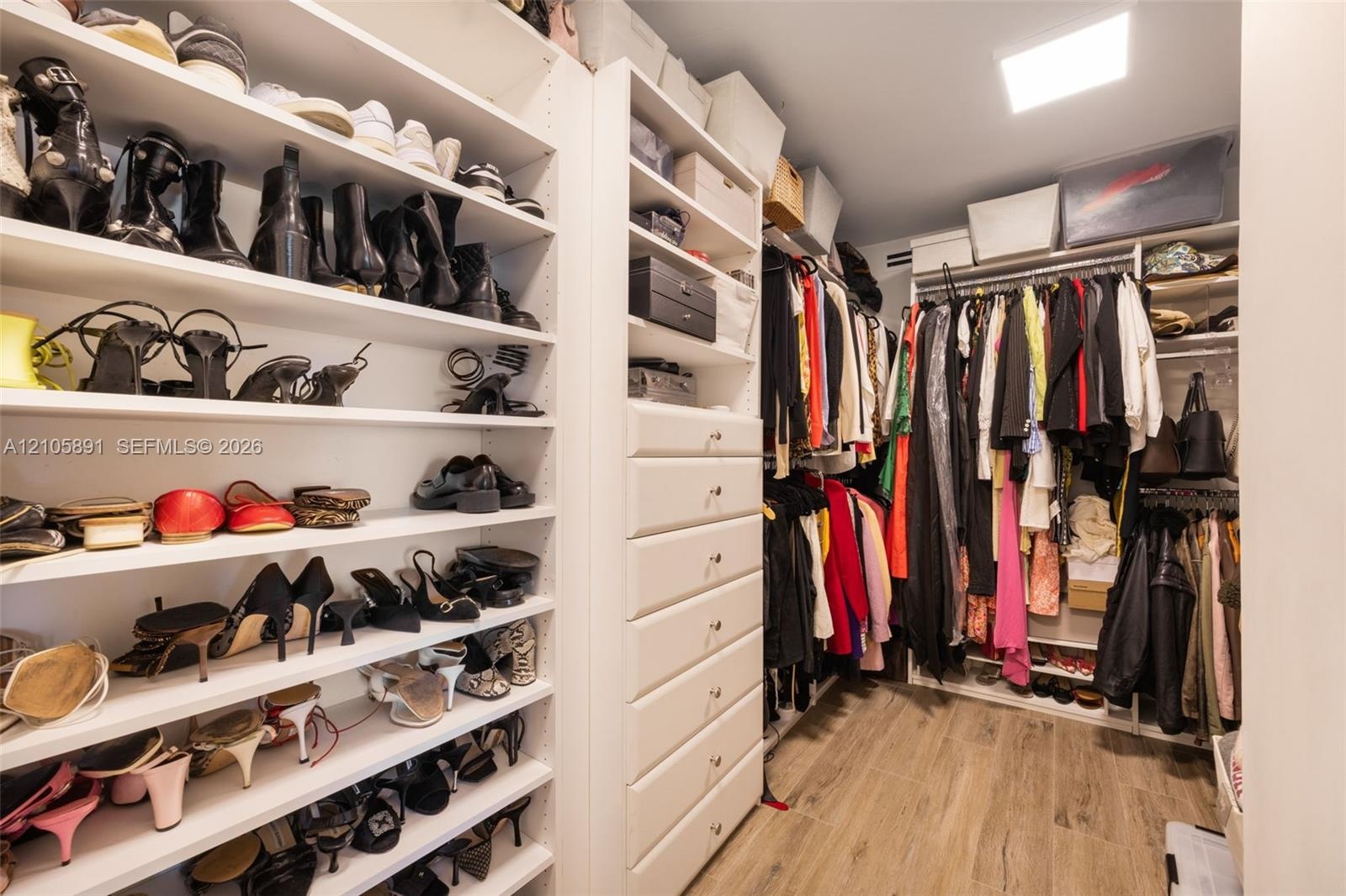 Custom dressing room featuring floor-to-ceiling adjustable shelving, integrated cabinetry with six soft-close drawers, dual-level hanging rods, and wo