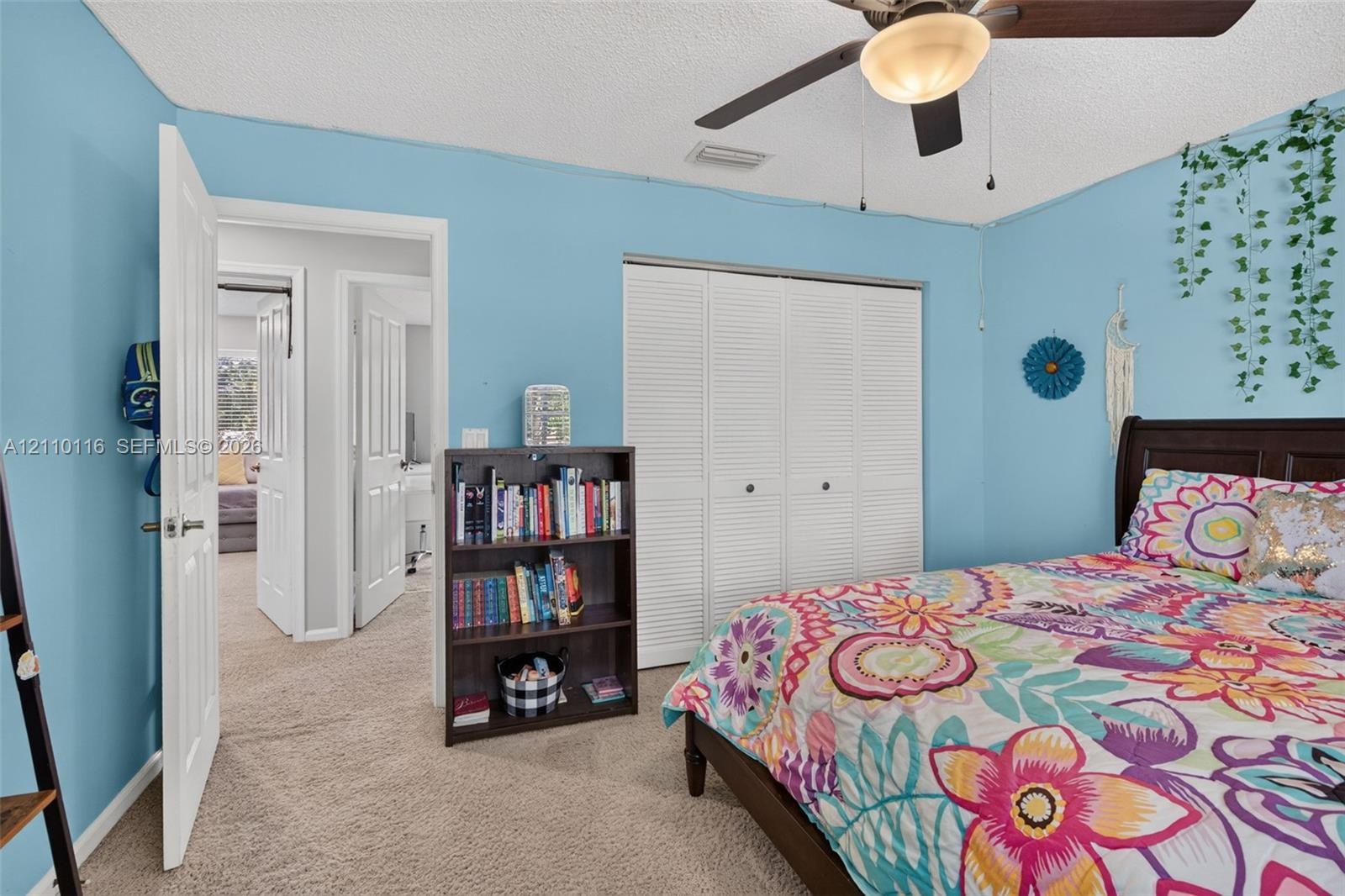 Bedroom featuring carpeted flooring, a ceiling fan with integrated lighting, and a closet with white louvered doors