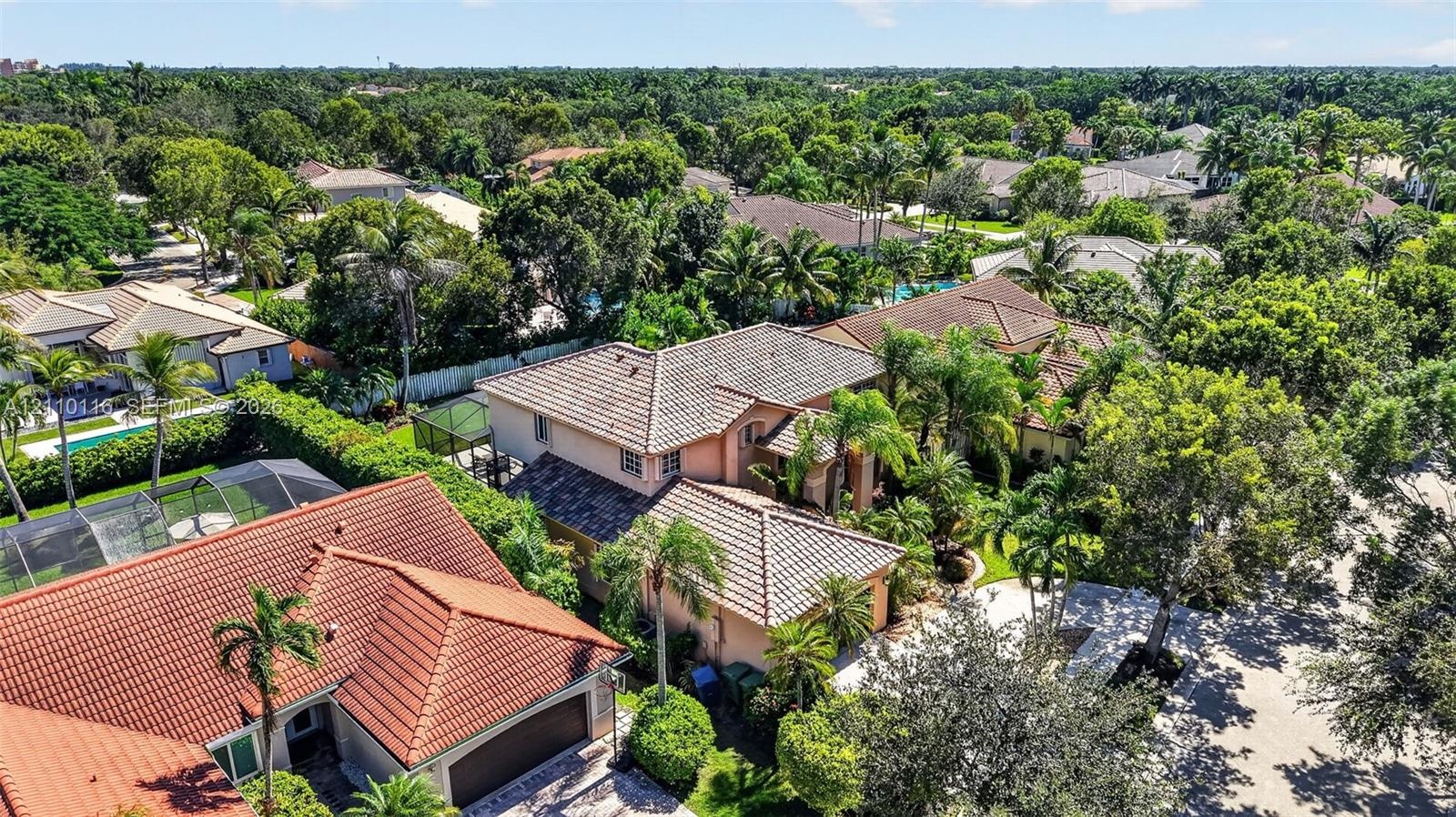 Aerial perspective featuring multi-level residences with tiled roofs, established landscaping, and paved driveways