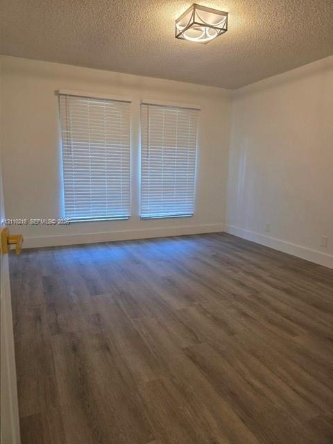 Room featuring wood-finish flooring, dual windows with horizontal blinds, and a geometric flush-mount ceiling light fixture