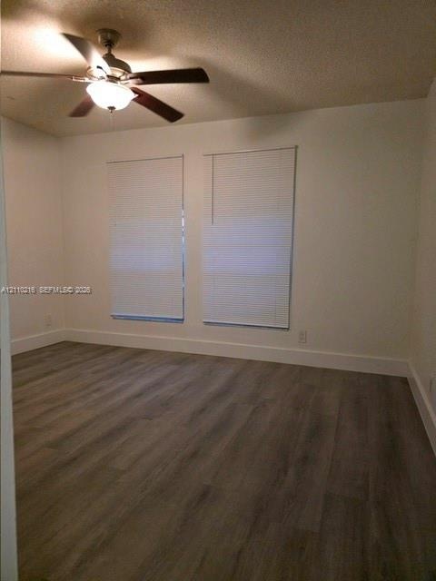 Interior space featuring wood-finish flooring, neutral wall paint, and a ceiling fan with integrated lighting, complemented by dual windows with insta