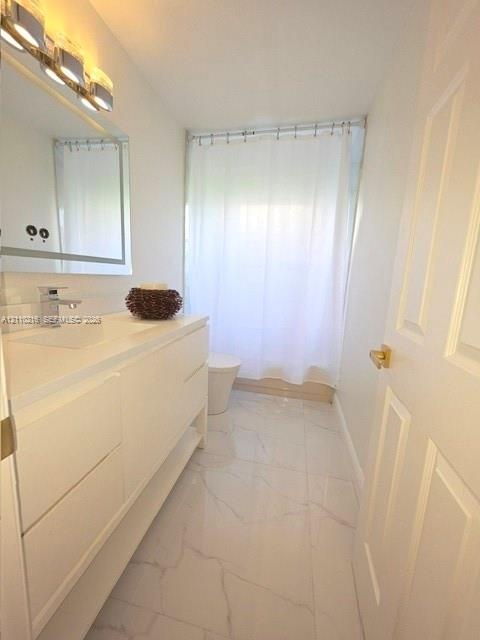 Bathroom featuring a modern white floating vanity with an integrated basin, polished metal faucet, multi-bulb vanity lighting, and light-toned tile fl