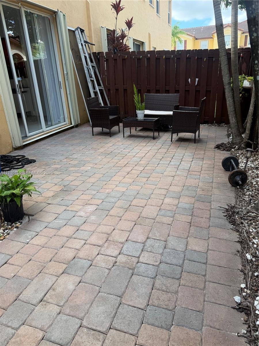 Private rear patio featuring concrete paver flooring, full-height privacy wood fencing, and sliding glass door access