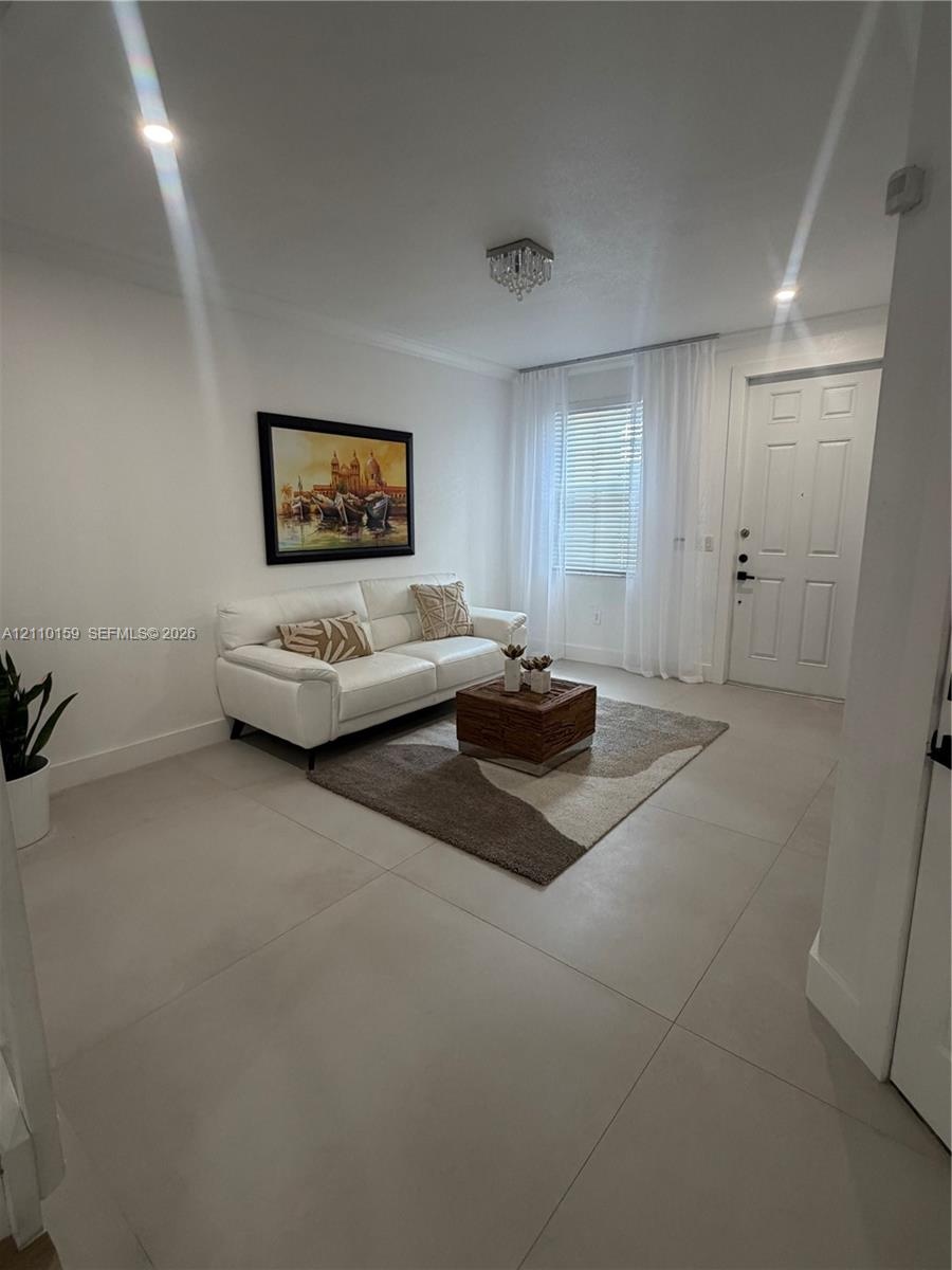 Large-format porcelain tile flooring, recessed lighting, crystal-style flush mount ceiling fixture, and a six-panel entry door