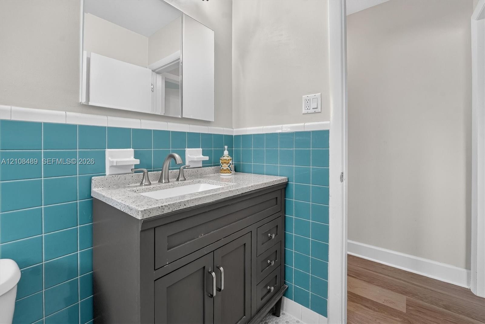 Vanity cabinet with shaker-style doors and drawers, speckled solid surface countertop, rectangular undermount sink, brushed nickel widespread faucet, 