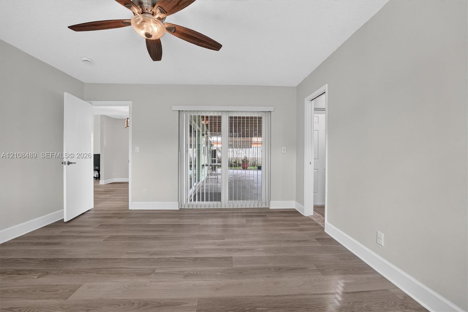 Room featuring wood-finish flooring, ceiling fan with light fixture, and sliding glass doors
