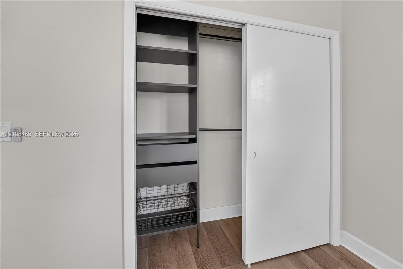 Reach-in closet featuring custom organizational cabinetry, including integrated shelving, dual storage drawers, and metal wire pull-out baskets, compl