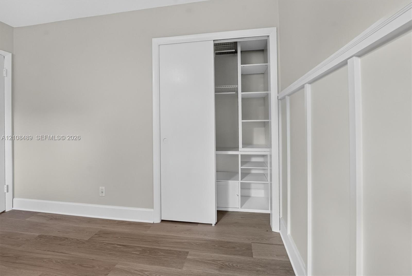 Wood-finish flooring, white board-and-batten wall detailing, and a sliding-door closet featuring built-in shelving