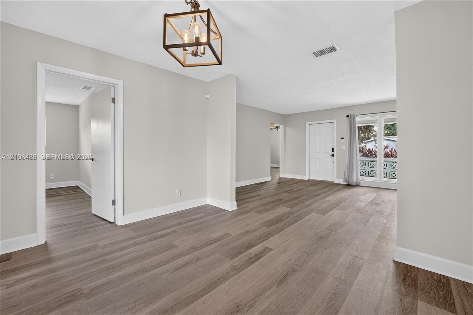 Interior space featuring wood-finish flooring, neutral wall paint, a geometric open-frame chandelier, and multi-lite exterior glass doors