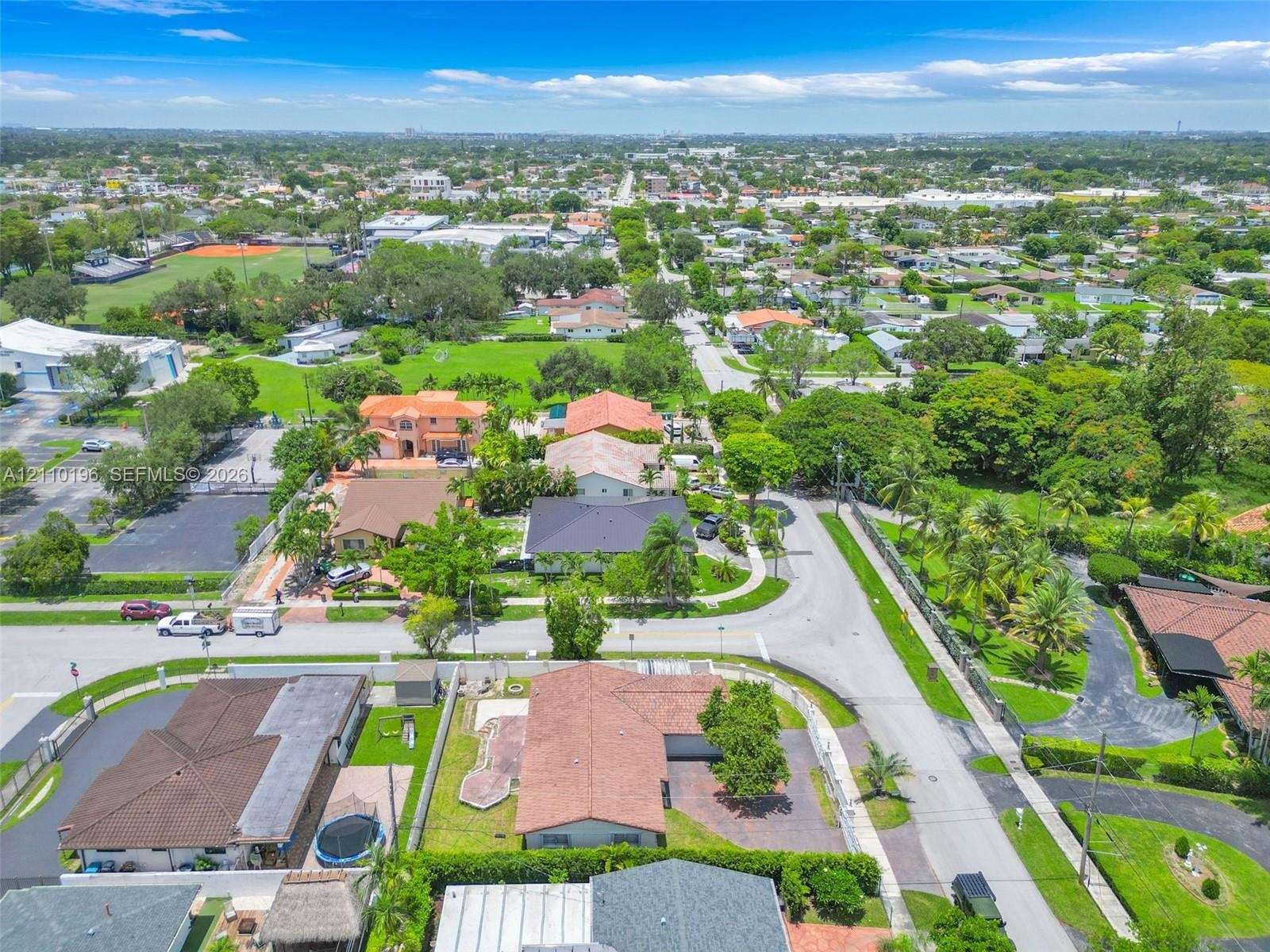 Aerial perspective of a suburban neighborhood featuring paved street infrastructure, mature landscaping, diverse residential roof styles, and abundant