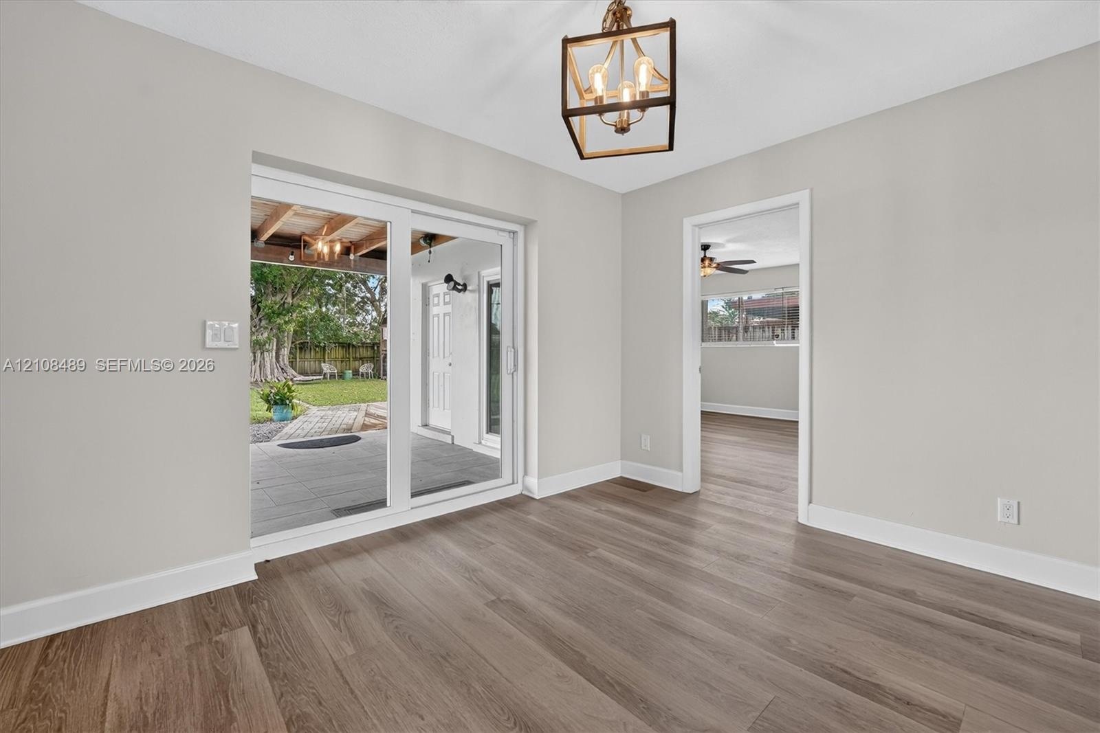 Wood-finish flooring, geometric-frame pendant lighting, and sliding glass doors with access to a covered patio