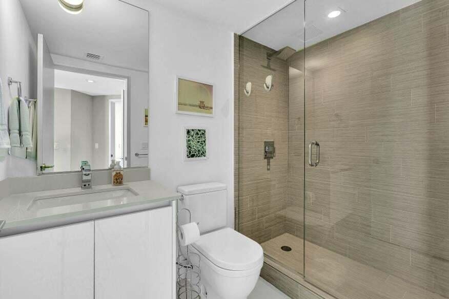 White vanity with a light-toned countertop, rectangular undermount sink, and a frameless mirror