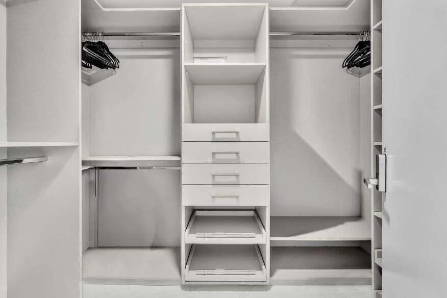 Custom closet system with multiple shelving units, integrated drawers, and chrome hanging rods