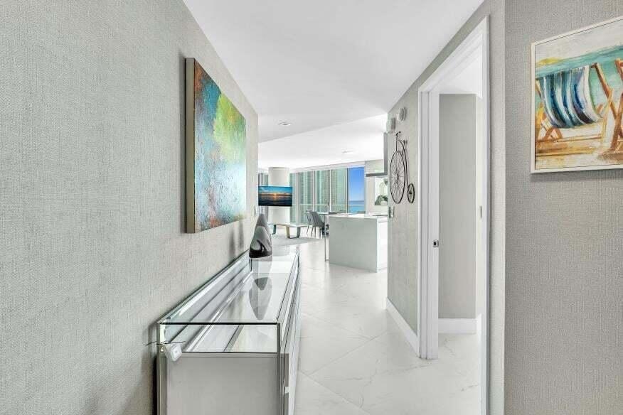 Hallway featuring textured wall coverings, recessed lighting, and white tile flooring