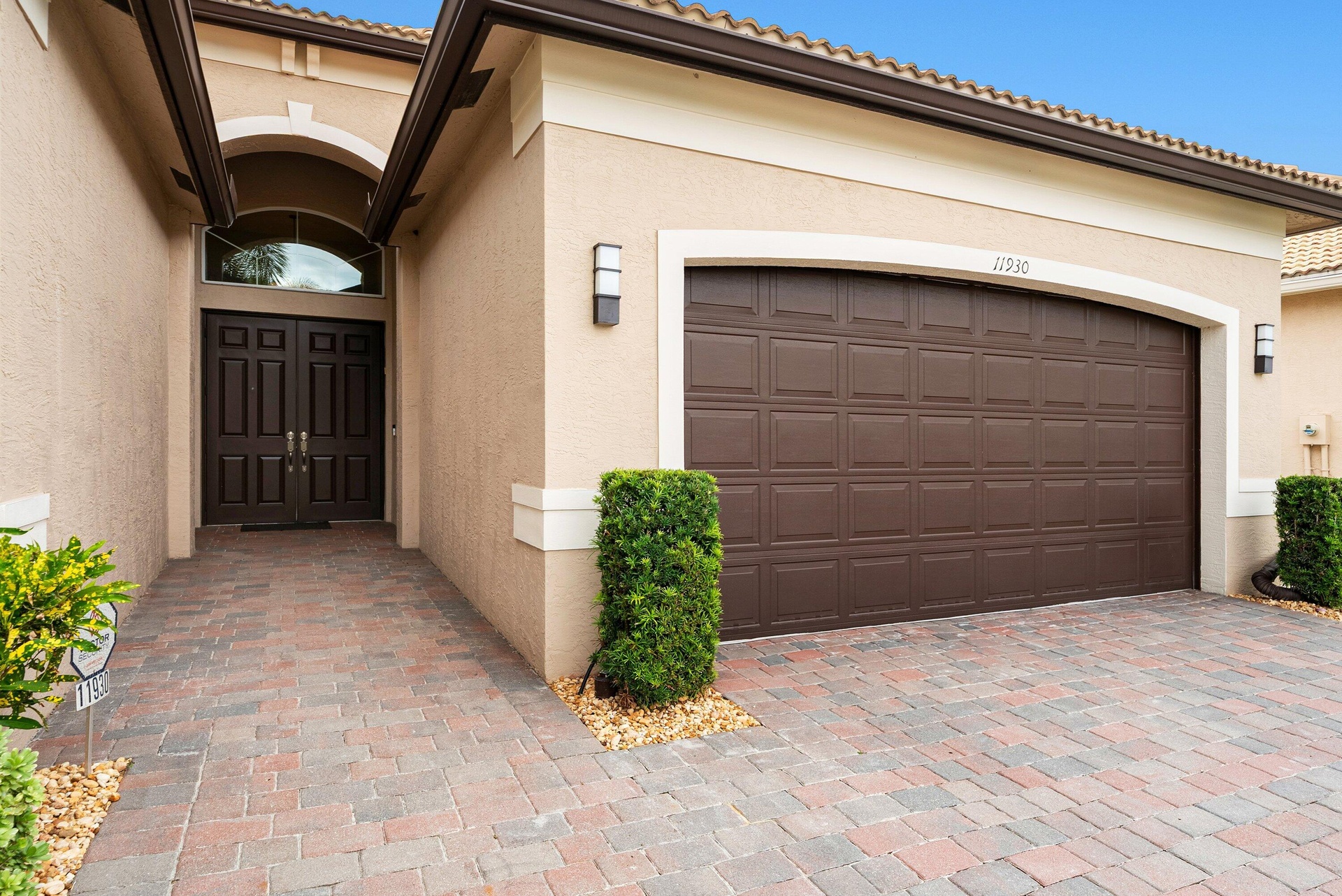 Stucco exterior featuring an arched entryway, double-panel front doors with a fanlight window, a multi-car garage with a raised-panel door, and a deco