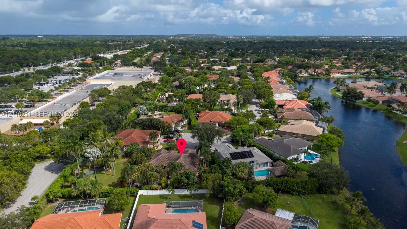 Aerial perspective of a residential property featuring a tiled roof, mature landscaping, palm trees, and a spacious lot